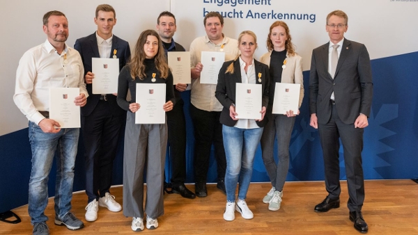Die Geehrten stehen mit Ministerpräsident Günther vor einer Wand mit der Aufschrift "Engagement braucht Anerkennung". Sie halten Urkunden in den Händen und tragen einen Orden an der Brust. (Quelle: Frank Peter) Die Geehrten stehen mit Ministerpräsident Günther vor einer Wand mit der Aufschrift "Engagement braucht Anerkennung". Sie halten Urkunden in den Händen und tragen einen Orden an der Brust.